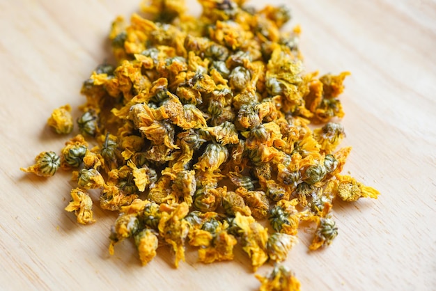 Dried chrysanthemum buds for herbal tea on wooden background, dry chrysanthemum flower yellow