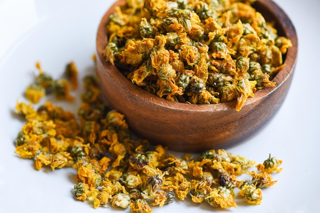 Dried chrysanthemum buds for herbal tea on wooden bowl, dry chrysanthemum flower yellow