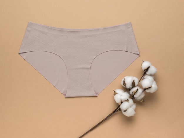 Dried cotton and beige women's underpants on a beige background Women's underwear Flat lay