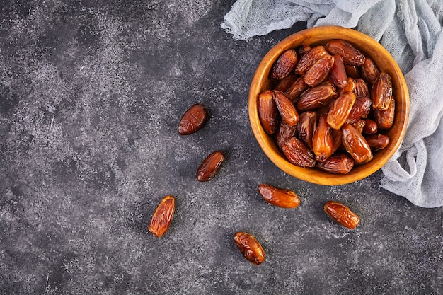 Photo dried date fruit in bowl on wooden. delicious dates fruit. top view