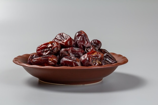 Dried dates on a clay plate with the gray background