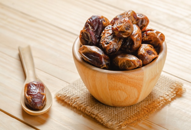 dried dates plam fruit in wooden bowl on table