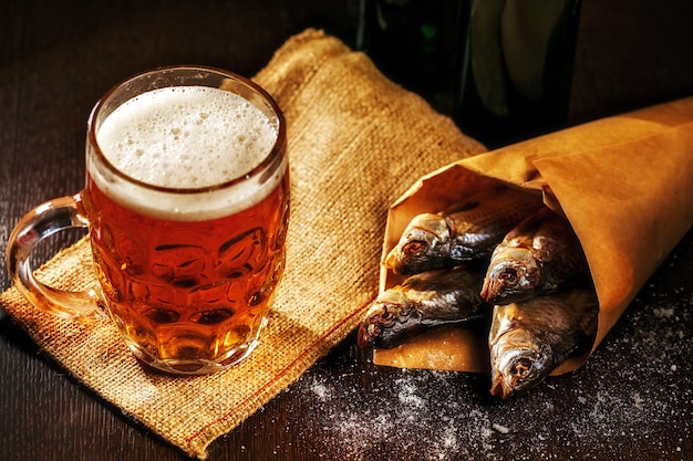 Dried fish and vintage glass of beer on a black surface