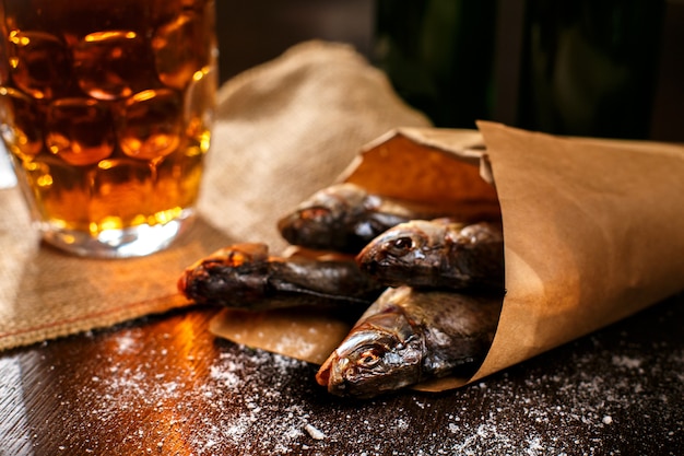 Dried fish and vintage glass of beer on a black surface