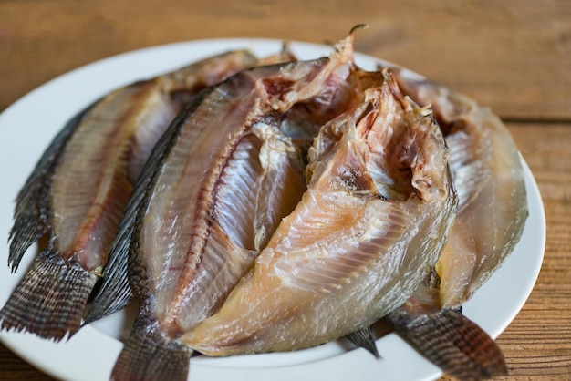 Dried fish on white plate tilapia fish for cooking food on wooden food preservation dry fish