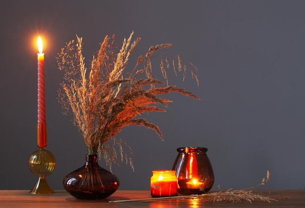 Dried flowers and burning candles on background dark wall