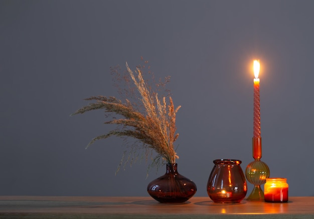 Dried flowers and burning candles on background dark wall