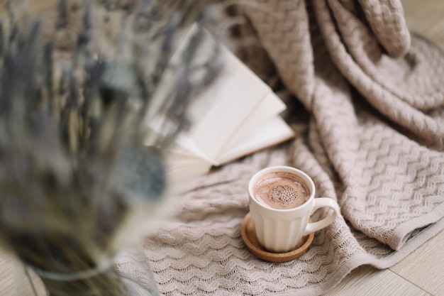 Dried flowers and a cup of cappuccino with book on wooden background top view