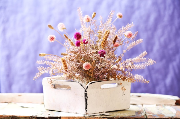 Dried flowers in pot on bright background