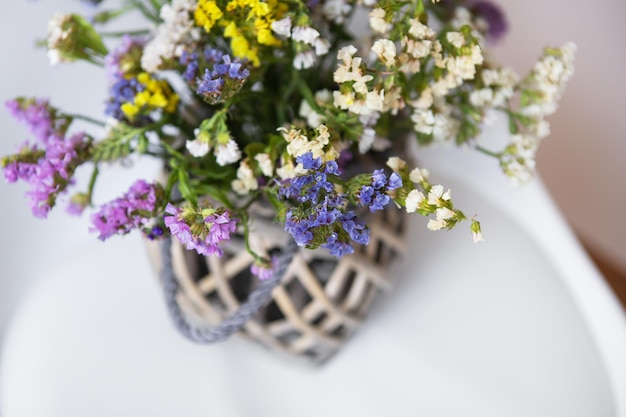 Dried flowers in a wooden vase stands on a white chair copy space Place for an inscription