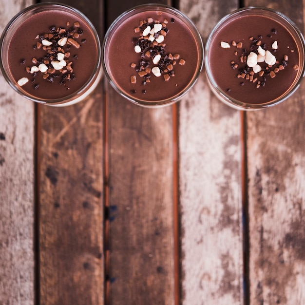 Dried fruits on chocolate glasses over wooden blurred desk