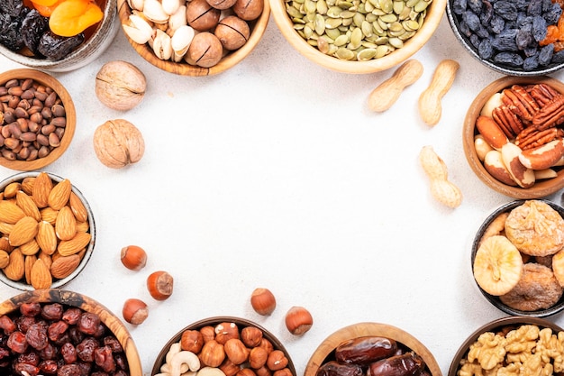 Dried fruits nuts in bowls set Dry apricots figs raisins walnuts almonds and other Healthy nutritious snacks White table background top view copy space