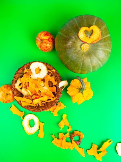 Dried fruits and vegetables slices apple pumpkin in brown wicker basket on green background Selective focus