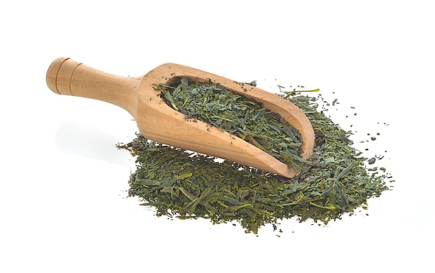 Dried green tea leaves in wood scoop on white background