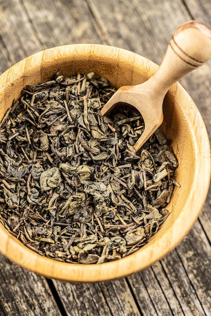 Photo dried green tea leaves in wooden bowl top view