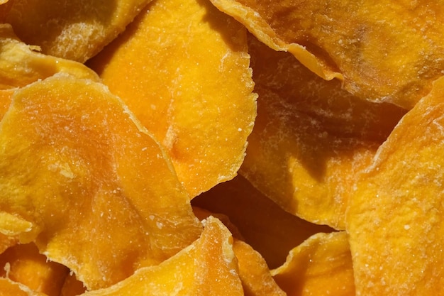 Dried mango slices closeup on a white Top view Closeup Mango chips background Dehydrated crispy fruit slices pieces Heap of sundried yellow fruit Healthy meal Top view flat lay