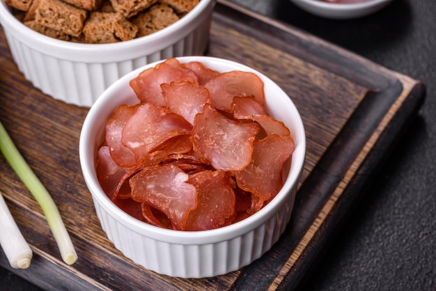 Dried meat slices with spices and herbs Snacks for beer On a black stone background Top view