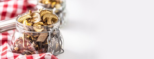 Dried mushrooms in a glass jar on a red checkered tablecloth.