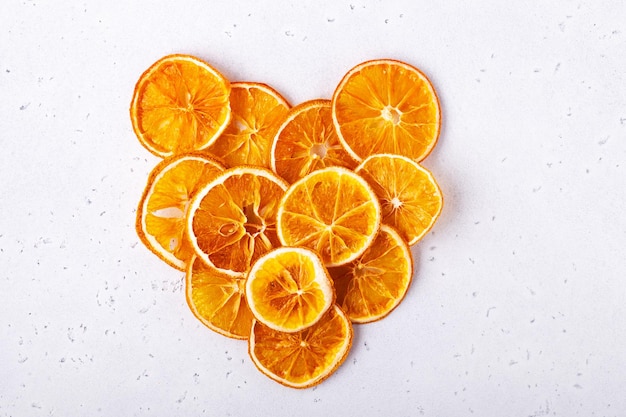 dried orange slices laid out in the shape of a heart on a white stone background