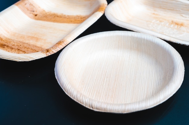 Dried palm leaf or betel nut and leaf dish plate disposable tableware product, zero waste environment concept, Natural eco-friendly organic food packaging on black background.