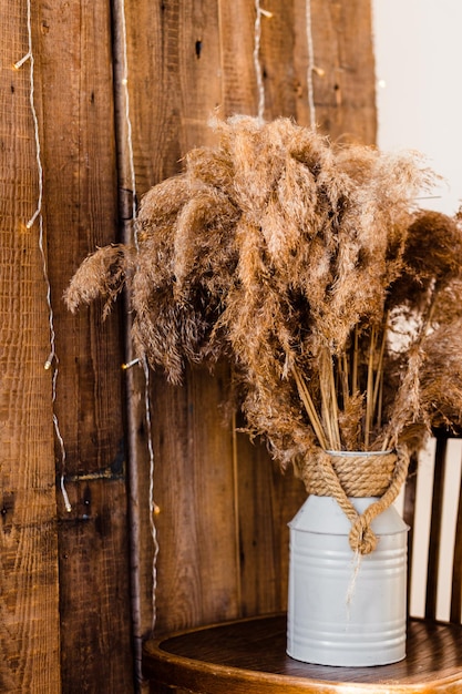 Photo dried pampas grass in rustic vase on wooden chair