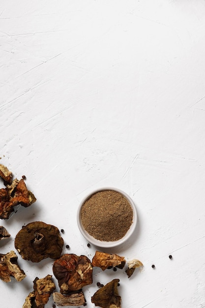 The dried porcini mushroom powder and dried mushrooms on white background, top view, copy space