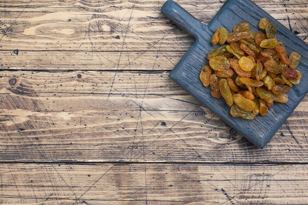 Dried raisins from white grapes on a wooden chopping board