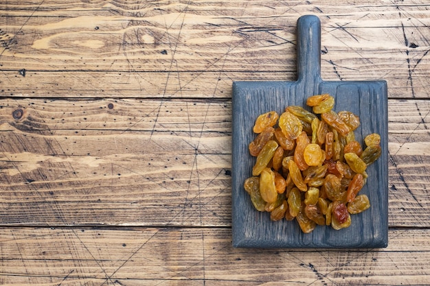 Dried raisins from white grapes on a wooden chopping board