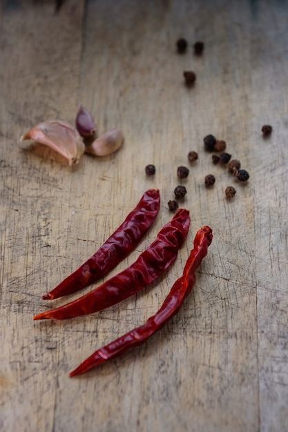 Dried red chili or chilli cayenne and back pepper on wood background