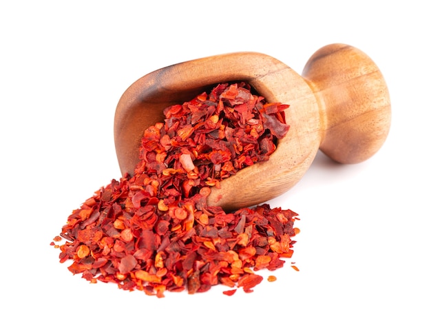 Dried red chili flakes in wooden scoop isolated on white background chopped chilli cayenne pepper