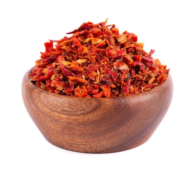 Dried red paprika flakes in wooden bowl isolated on white background Spices and herbs