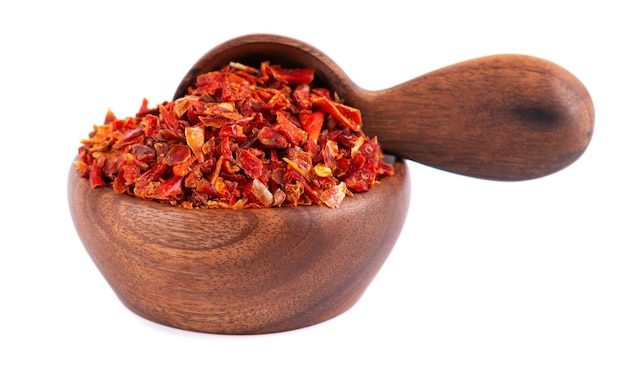 Dried red paprika flakes in wooden bowl and spoon isolated on white background Spices and herbs