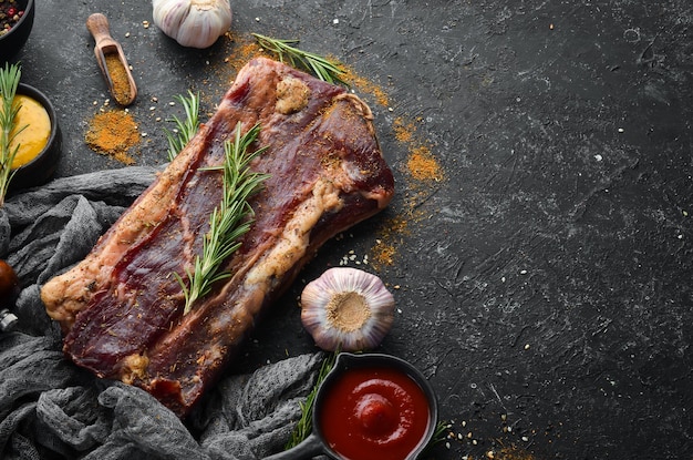 Dried salted meat with rosemary and spices Jamon On a black stone background Top view