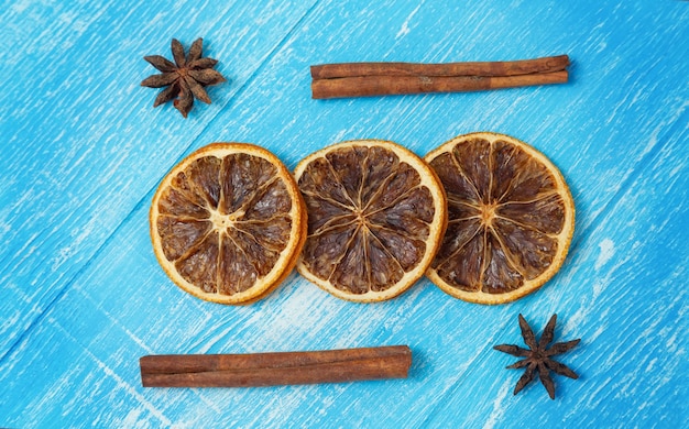 Dried slices of lemon, cinnamon and anise lie on a blue wooden .