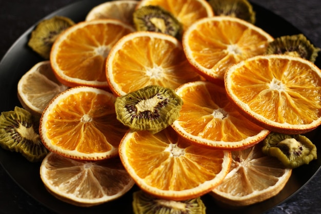 Dried slices of orange lemon kiwi on a dark background