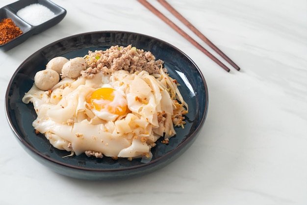 Dried spicy noodles with minced pork meatballs and egg