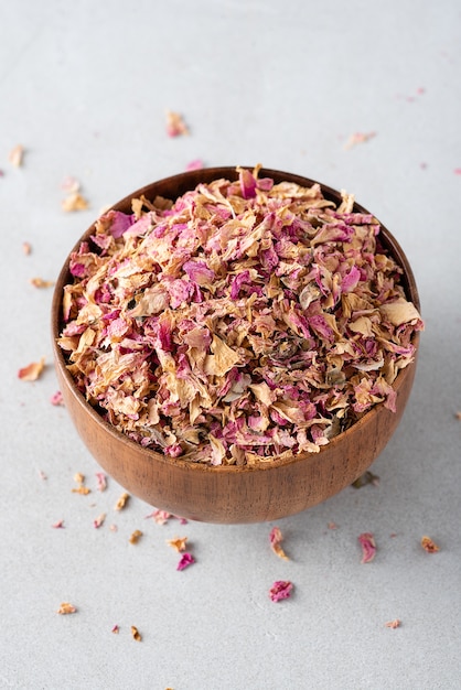 Dried tea rose petals in a wooden bowl