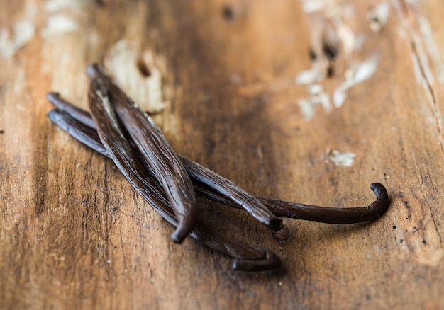 Dried vanilla sticks and vanilla orchid on wooden table. Close-up.