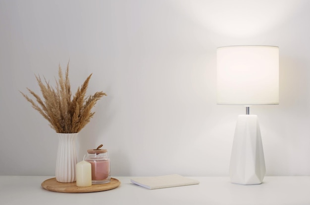 dried wild flowers in white vase on wooden shelf on background white wall