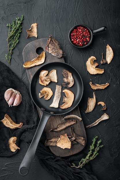 Dried wild mushrooms set in cast iron frying pan, on black