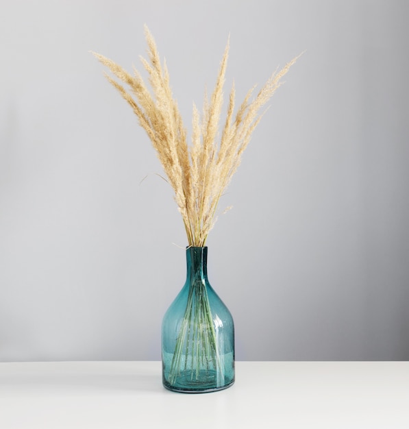 Dried yellow decorative cereals in glass vase on  white table