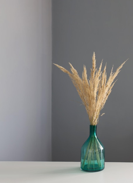 dried yellow decorative cereals in glass vase on white table