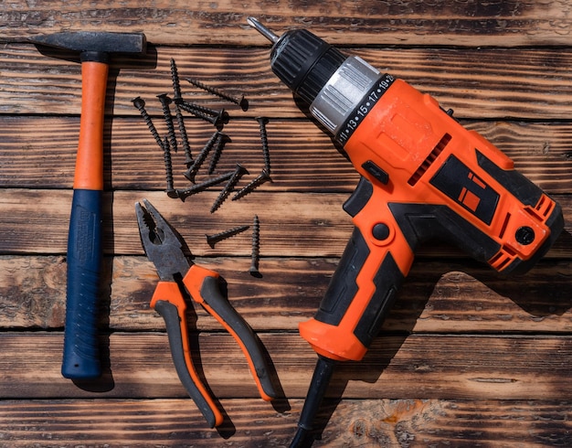 Drill screwdriver hammer cutters and nails on a work desk