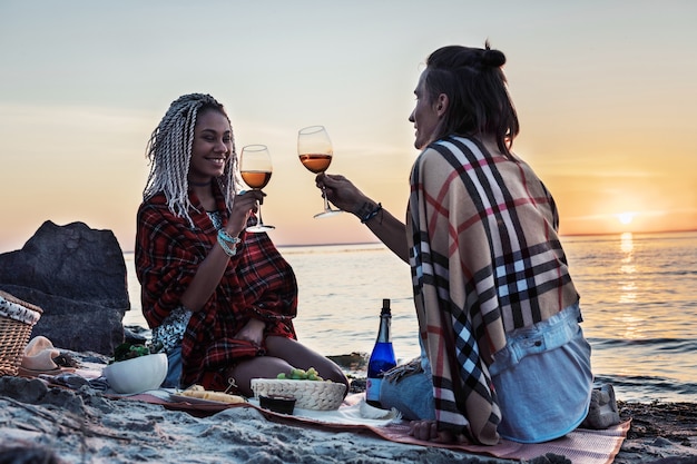 Drink champagne. Beaming woman with dreadlocks drinking champagne with her man having picnic