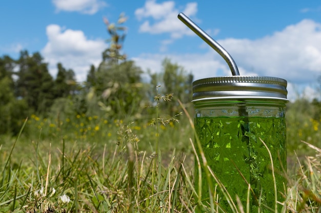 Drink in glass with straw on background of summer meadow and blue sky Close-up