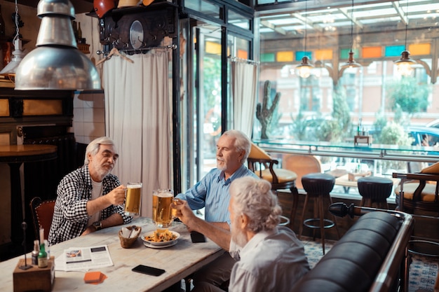 Drinking beer together. Three men feeling good while drinking beer together in the pub