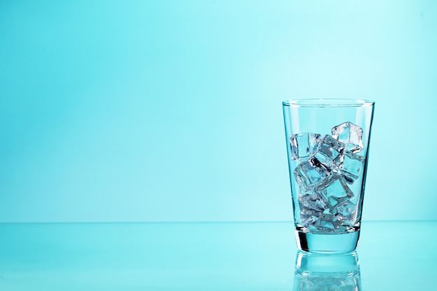 Drinking glass with ice cubes on the blue background