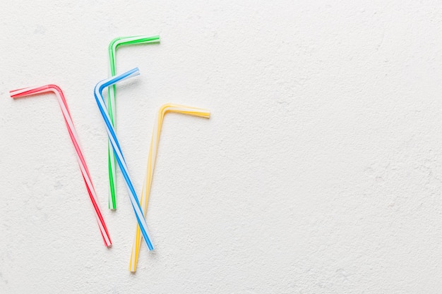 Drinking straws for party on Colored background. Top view of colorful plastic disposable straws for summer cocktails. different straws for juice with copy space