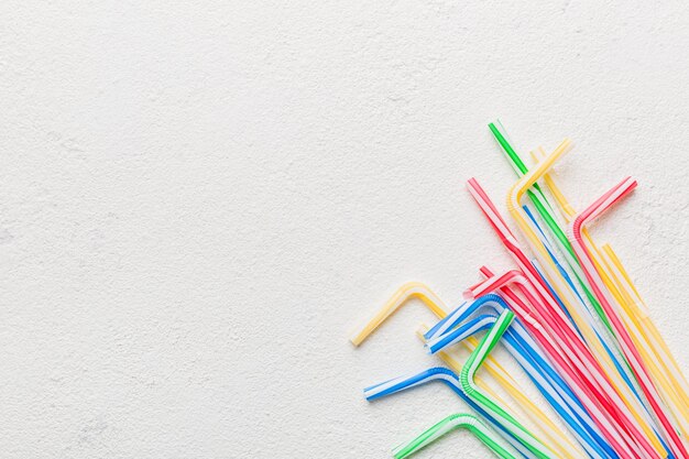 Drinking straws for party on Colored background. Top view of colorful plastic disposable straws for summer cocktails. different straws for juice with copy space