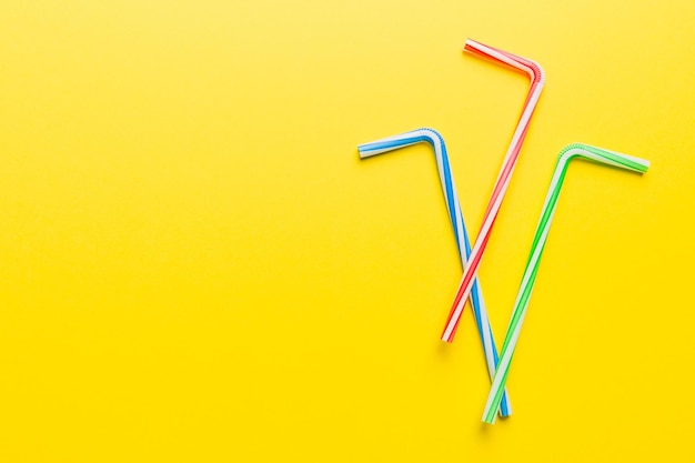 Photo drinking straws for party on colored background top view of colorful plastic disposable straws for summer cocktails different straws for juice with copy space